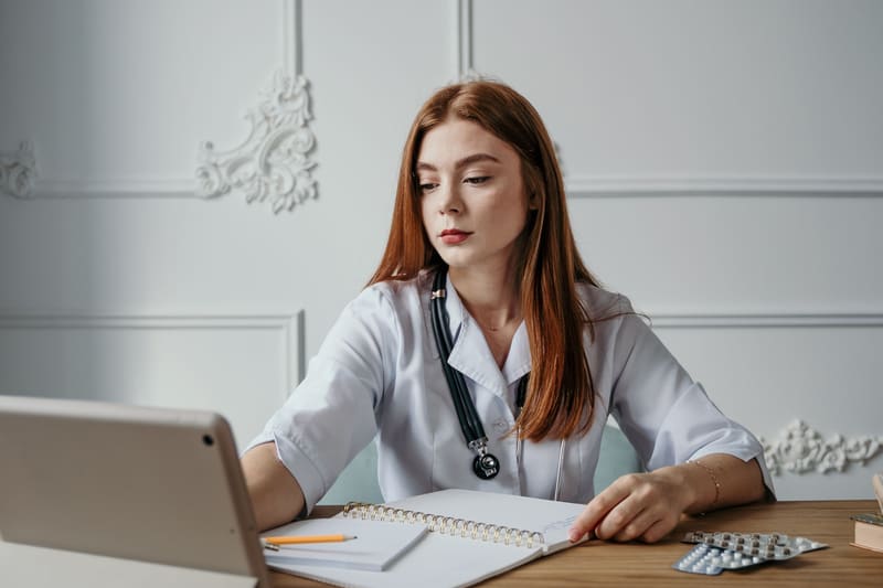 Healthcare professional studying with a laptop and notebook